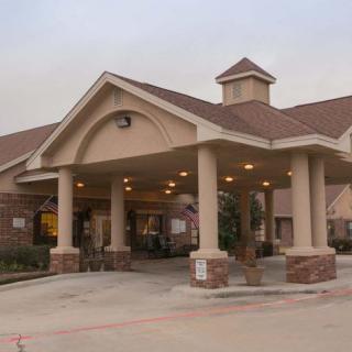 The exterior view of a building with a covered entrance supported by pillars.