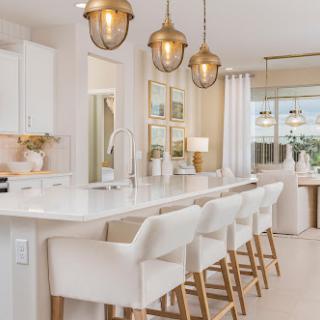 A modern kitchen featuring elegant pendant lighting and stylish bar stools, creating a bright and inviting atmosphere.