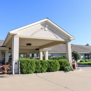 A building entrance with a covered driveway and landscaped surroundings.