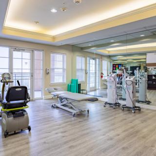 A spacious and well-lit gym with modern exercise equipment and mirrors.