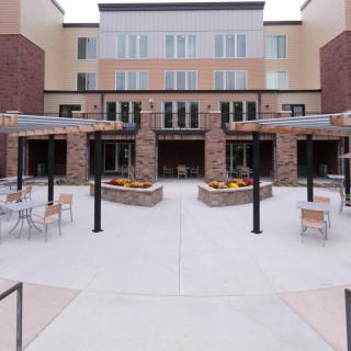 A modern building with a courtyard featuring outdoor seating areas.