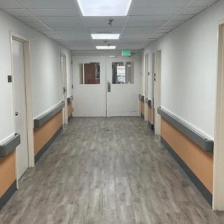 A clean and empty hospital hallway with closed doors and overhead lights.