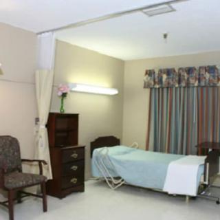 A simple hospital room with a bed, chair, and curtains.