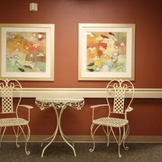 A cozy sitting area with two ornate chairs, a small round table, and abstract artwork on the wall.