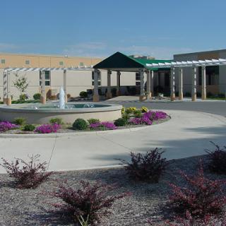 A serene courtyard featuring a fountain surrounded by vibrant landscaping and outdoor seating.