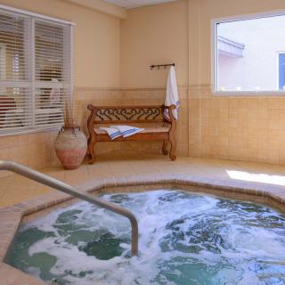 An inviting indoor hot tub area with bubbling water, a wooden bench, and large windows.