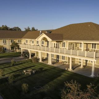 A large two-story building with a spacious lawn and an extensive balcony under a clear blue sky.