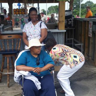 A group of people enjoying a day outdoors, including one sitting in a wheelchair wearing a hat.