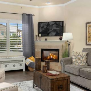 A cozy living room with a fireplace, a comfortable sofa, and a TV mounted above the mantel.