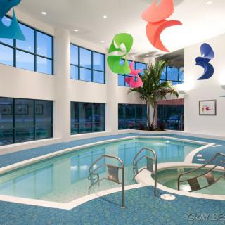 A modern indoor swimming pool with colorful hanging decorations and a large palm tree.