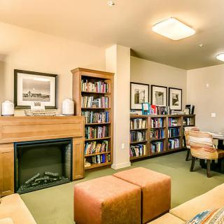 A cozy library with bookshelves, a fireplace, and comfortable seating.