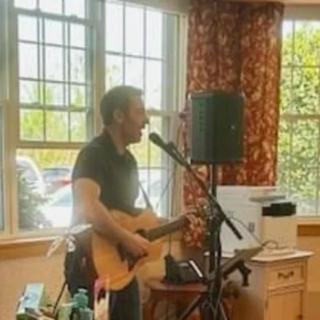 A musician performing with a guitar and microphone indoors.