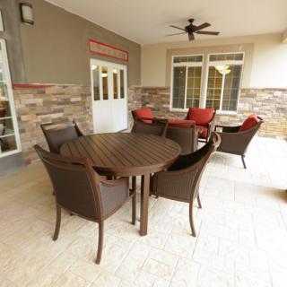 A cozy outdoor patio featuring a round table surrounded by chairs and a comfortable seating area against a brick wall.