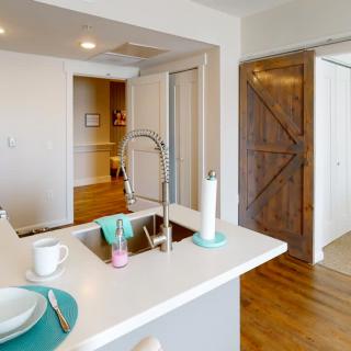 A modern kitchen with a sleek countertop, featuring a dining area and a stylish barn door.