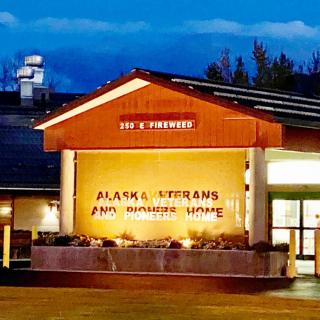 A nighttime view of the Alaska Veterans and Pioneers Home, illuminated with exterior lights.