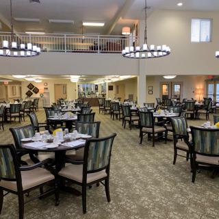 A spacious dining room with elegantly set tables and modern chandeliers.