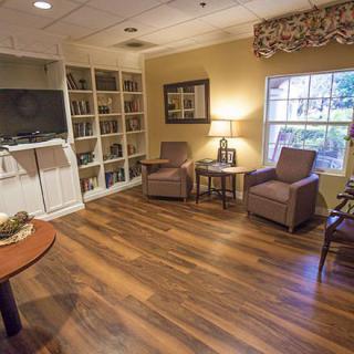 A cozy living room with comfortable seating and a bookshelf, featuring wooden floors and soft lighting.