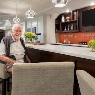 An elderly man enjoying a moment at a stylish bar setting, surrounded by modern decor.
