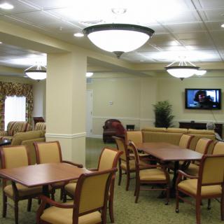 A well-lit dining area with tables and chairs, featuring a television on the wall.