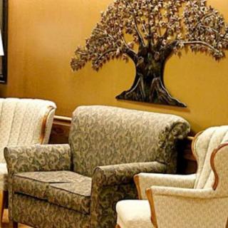 A cozy living room setup featuring patterned armchairs and decorative wall art of a tree.