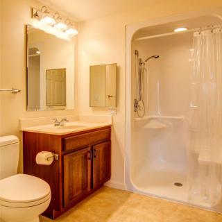 A clean and well-lit bathroom featuring a shower, vanity with sink, and toilet.