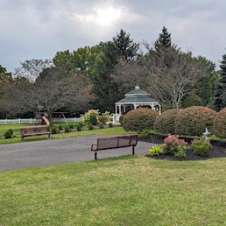 A serene park scene featuring a gazebo, benches, and well-maintained greenery.