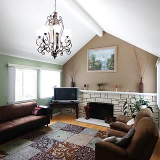A cozy living room with a chandelier, sofas, a fireplace, and TV.