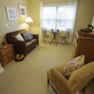 A cozy living room featuring a sofa, armchair, and a small table with chairs near the window.