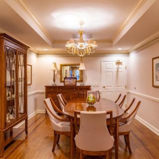 An elegant dining room with a chandelier, wooden table, and upholstered chairs.