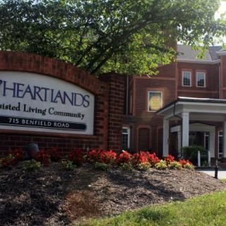 Entrance to Heartlands Assisted Living Community with a welcoming sign and landscaped surroundings.