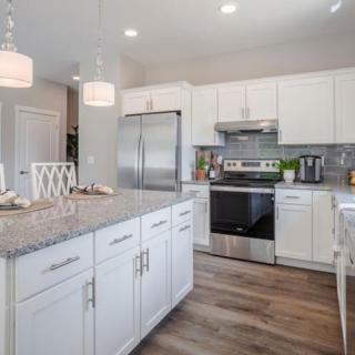 A modern kitchen with white cabinets, granite countertops, and stainless steel appliances.