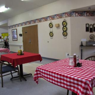 A cozy dining area featuring checkered tablecloths and condiments on the tables.
