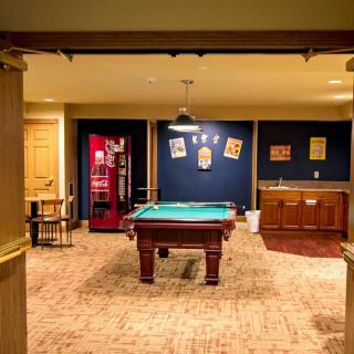 A cozy game room featuring a pool table, wall decorations, and a small bar area.