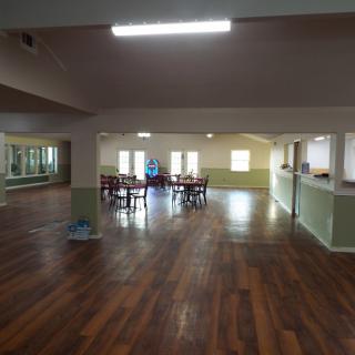 An indoor space with wooden flooring, featuring tables and chairs.