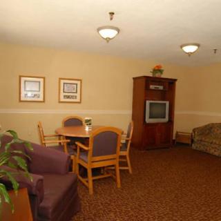 A cozy living room area with a table, chairs, sofa, and a television surrounded by warm lighting.