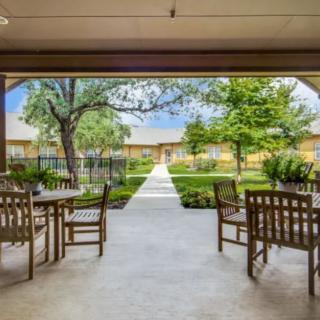 A tranquil patio with wooden chairs overlooks a garden path leading through lush greenery.