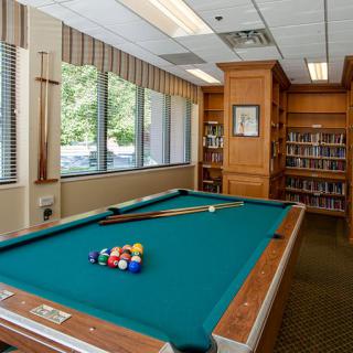 A cozy recreational room featuring a pool table and a small library.