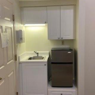 A compact kitchenette with a sink, cabinets, and a small refrigerator.