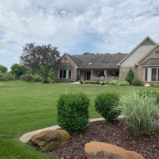 A suburban house with a well-maintained lawn and garden on a cloudy day.