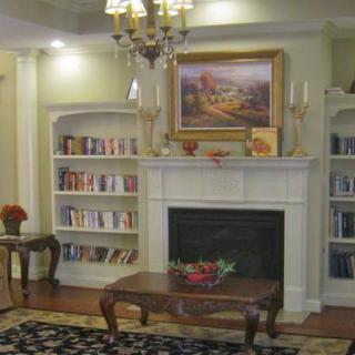 A cozy living room with bookshelves, a fireplace, and elegant decor.