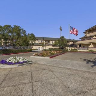 A building with landscaped grounds and a large American flag waving in the parking area.