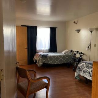A cozy bedroom with a single bed, wooden flooring, and simple furnishings.
