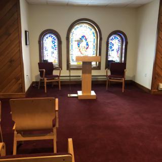 Small chapel interior with stained glass windows and a podium.