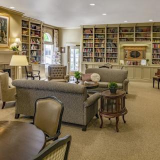 A cozy living room with bookshelves, comfortable seating, and warm lighting.
