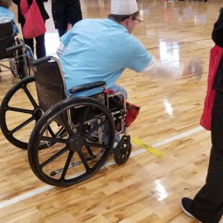 A participant in a wheelchair engages in an indoor recreational activity.