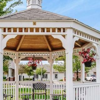 A charming white wooden gazebo with hanging flowers, located in a serene garden setting.
