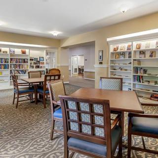 A cozy library with tables, chairs, and well-stocked bookshelves.