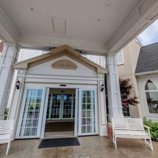 The entrance to a hotel, featuring double glass doors and white benches.