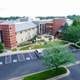 Aerial view of a modern brick building with a surrounding parking lot and landscaped grounds.
