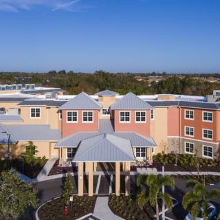 Aerial view of a modern building with a landscaped entrance and clear blue sky.